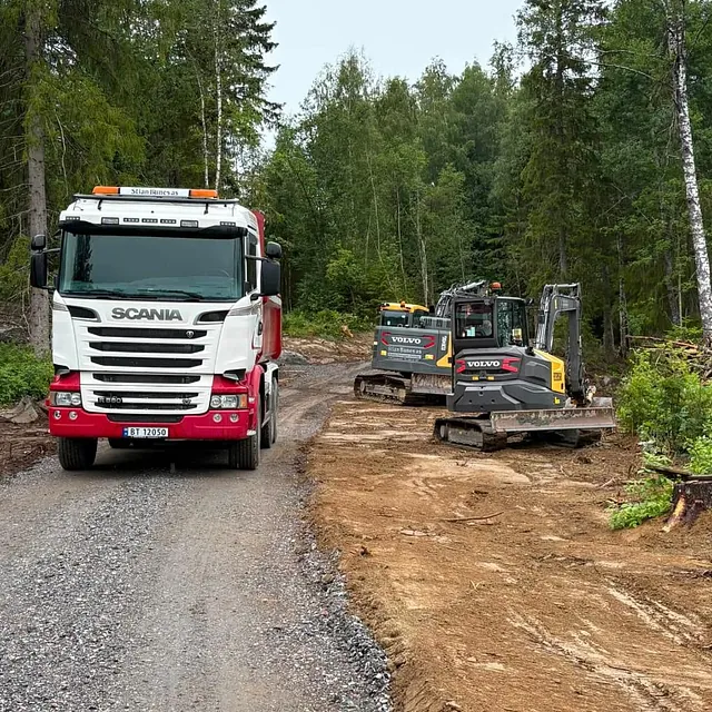 Lastebil og gravemaskiner på anleggsvei i skogen